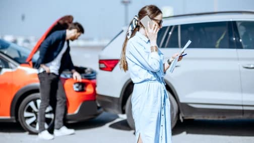 道路脇で車の故障を確認する男性と電話をする女性の輸入車トラブル